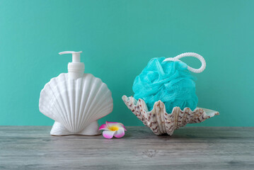 The synthetic shower sponge and liquid soap in the bottle are decorated with a seashell.  A blue...