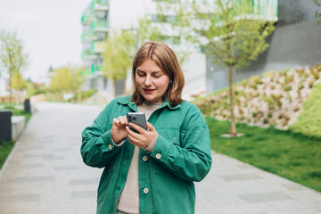 30s cheerful woman tourist dressed in casual look holding smartphone gadget in hand for communicate...