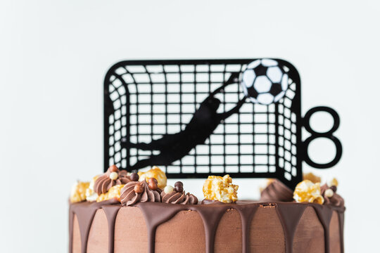recommend clip art: Birthday cake for a football fan with brown cream cheese frosting and chocolate drips decorated with goalkeeper silhouette tackles the ball.