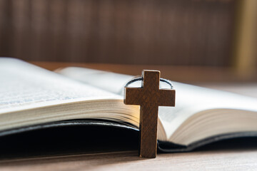 Wooden cross necklace next to open bible, Christian concept, religious symbol