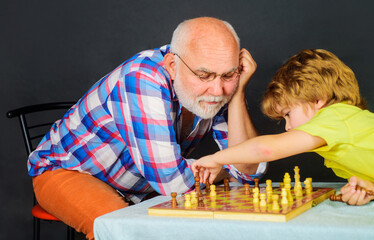 Grandfather teaching grandson to play chess. Childhood and board logic games. Child boy plays chess...