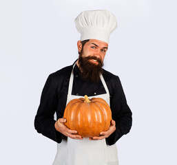 Smiling male chef in white apron with pumpkin. Organic food. Harvest festival. Bearded man in chef...
