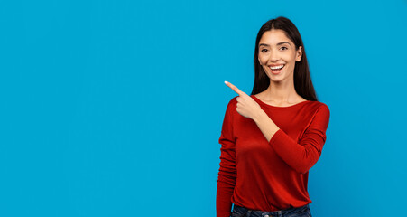 A woman is pointing at an object or direction using her index finger. She appears focused and engaged in the action, possibly indicating a specific item or giving directions, blank space