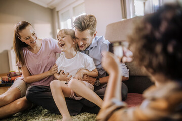 Family playing together on living room floor while being photographed