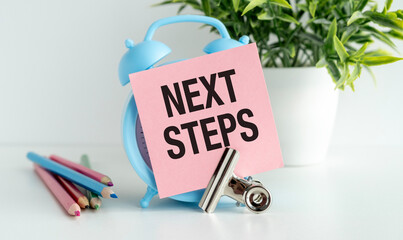 Next Steps text on clock. Text on office paper notepad
