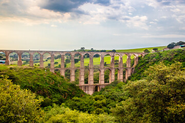 Aqueduct between mountains at sunset with cloudy sky in arcos del sitio in tepotzotlan state of mexico