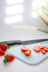 Some fresh red strawberries on a cutting board along with a knife on a white background