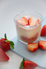 A homemade natural yogurt with fresh red strawberries on a cutting board