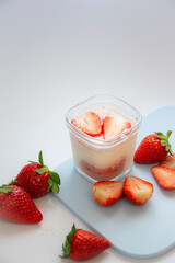 A homemade natural yogurt with fresh red strawberries on a cutting board