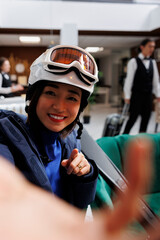 Youthful asian woman at exclusive ski resort holding cellphone for selfie picture. Enthuisiastic...