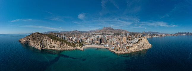 Extremely wide panoramic aerial drone photo of the town of Benidorm in Spain in the summer time showing the beach known locally as Playa de Finestrat and hotels and apartments around the small beach