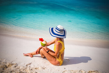woman with straw hat sunbathing on tropical beach