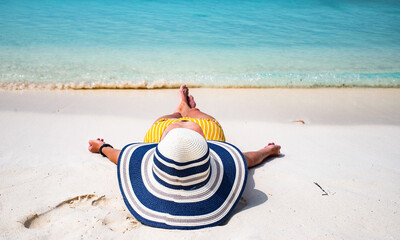 woman with straw hat sunbathing on tropical beach