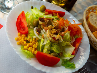 Appetizing Spanish salad with goat cheese and fresh vegetables served on plate