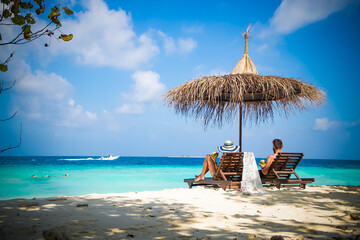 couple relaxing on tropical beach chairs