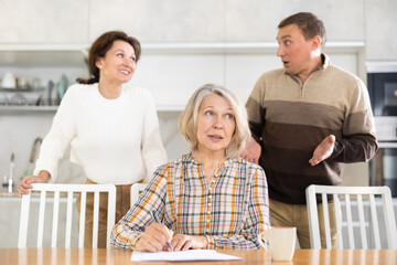 Old woman deciding and signing inheritance papers in family circle
