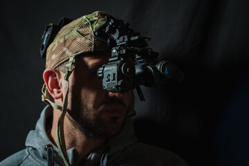 Portrait of a military contractor with a beard with a binocular night vision device on his head.