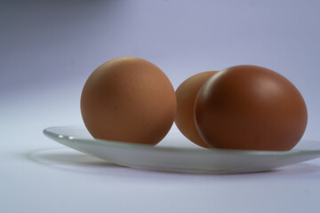 Fresh eggs on transparent plate against white background. Ideal for breakfast concepts. Simple, elegant culinary photography.