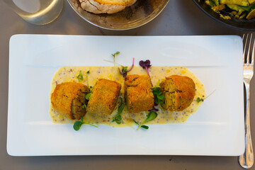 Top view of pan-fried pieces of French Andouillette served with mustard sauce and greens