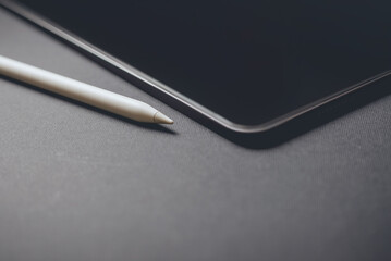 Close-up of a tablet and a pencil on a gray background
