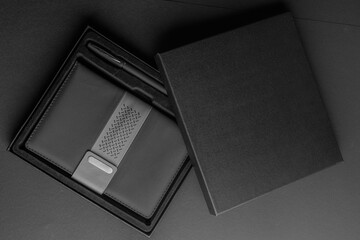 Top view of black box with stationery on black background. Flat lay.