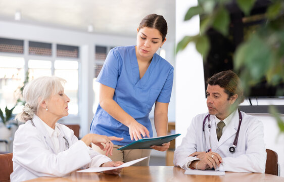 three doctors are sitting at table animatedly and actively discussing work
