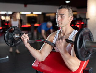 Sporty man performing set of exercises with barbell during intense workout. Concept of weight...