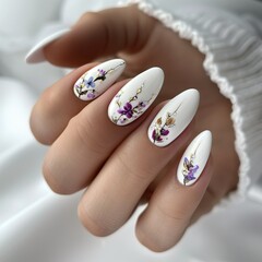 Dłoń kobiety ozdobiona białymi i fioletowymi kwiatami, w tle delikatne jasne tło. Obrazuje elegancję i subtelność