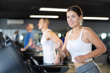 Young athletic woman in sportswear training on treadmill in gym