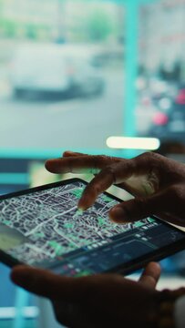 Vertical Video Manager tracking a delivery car by using satellite map for navigating around the city, monitoring orders via surveillance footage and CCTV system. Locating coordinates for shipping