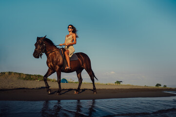 Woman rider riding her horse at the seacoast during an evening sunset