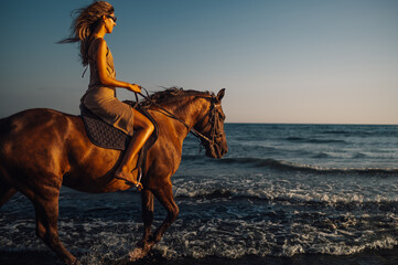 Beautiful woman galloping on a horse on an ocean coast beach