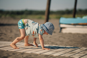 A little boy is trying to stand up while playing a game at the beach.