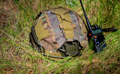 A helmet, and a walkie-talkie on the ground on a sunny day. Military equipment, military protection. 