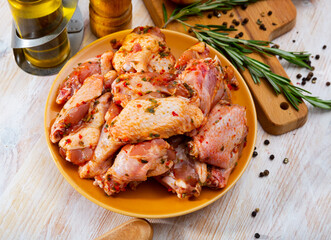 Plate with spicy marinated chicken wings prepared for family picnic on table with condiments and...