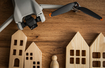 Drone on a table with wooden houses Drone surveillance concept, Uav in urban environments,...