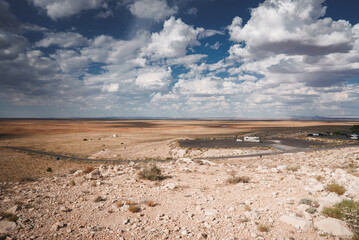 Landscape in Arizona with Meteor Crater, rocky terrain, and vast sky. Features a visitor center at the crater's rim for scale. Isolated and grand scenery.