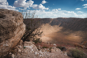 Impressive desert crater with rocky edges and sparse vegetation in Meteor Crater, Arizona, USA....