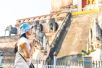 Naklejka premium Happy Asian woman traveler enjoy and fun outdoor lifestyle travel in Thailand on summer holiday vacation. Attractive girl tourist travel old traditional Buddhist temple in Chiang Mai. 