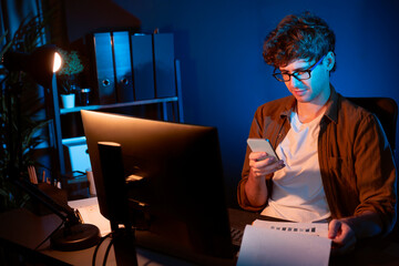 Young businessman using smartphone to search email, chatting with customer or coworker with holding...