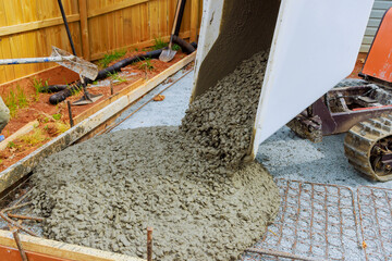 In course construction of foundation, wet cement is poured into framework from concrete buggy...