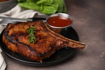 Tasty grilled meat, rosemary and marinade on brown textured table, closeup