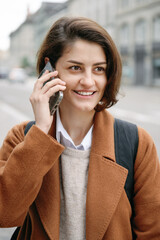 Young woman wearing warm clothes talking to the mobile outdoors