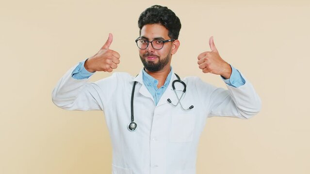 I am the best. Happy satisfied selfish Indian young doctor cardiologist man proud of victory triumph bragging own success win achievements. Arabian apothecary pharmacy guy isolated on beige background