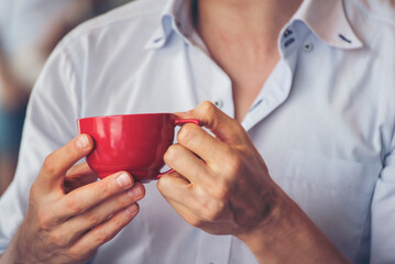 Close up hands of man sitting office desk holding sweet coffee cup relax and enjoy with happy time. Hot coffee mug in hand. Man holding coffee cup relaxing after work at office warm taste in cafe