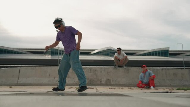 Group of asian break dancer perform street dance with multicultural friend support and moving hip hop music. Attractive handsome hipster practice b boy dance at street. Outdoor sport 2024. Sprightly.