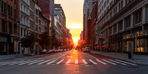 Empty streets and sidewalks at 5th Avenue and 23rd St in New York City with sunset shining between...