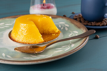 Small quindim, traditional Brazilian sweet, next to a spoon, coffee cup and a candle_4.