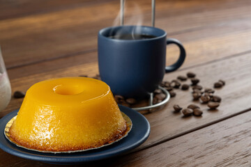 Small quindim, traditional Brazilian sweet, next to a cup of coffee and a candle_6.