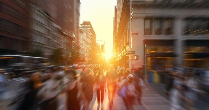 Crowds of people walking across the busy intersection at 23rd Street and 5th Avenue in New York City with the light of sunset background and motion blur